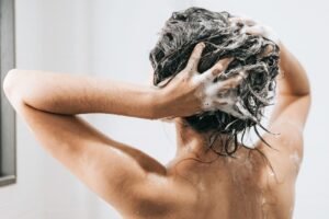 Mujer lavando su cabello y masajeando suavemente el cuero cabelludo